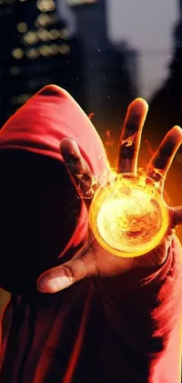This live wallpaper features a digital art depiction of a mage or sorcerer, donning a bright red hoodie and holding a glowing fireball in their hand