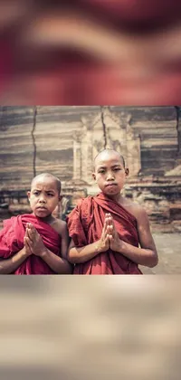 This phone live wallpaper features two youthful monks standing in repose in front of a stunning background image
