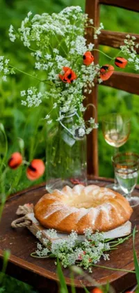 This phone live wallpaper features a cake and wine on a rustic wooden table, surrounded by lush greenery, red poppies, and ferns