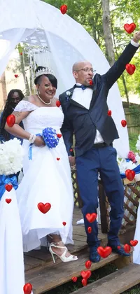 This live phone wallpaper showcases a happy couple wearing a tuxedo and wedding dress respectively, jumping and celebrating together against a lively blue background