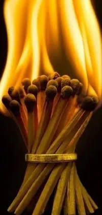 This live phone wallpaper showcases a visually striking image of matches arranged on a table, with bright yellow flames bursting from their tips