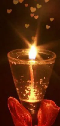 This mobile live wallpaper showcases a serene scene of a lit candle on a tabletop, accompanied by a glass-cast heart and artwork in the background