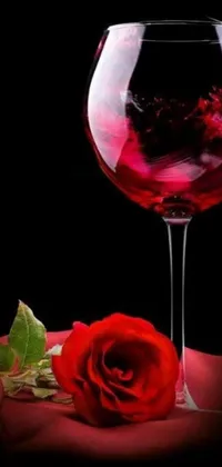 This captivating phone live wallpaper features a person holding a glass of wine and a lovely rose