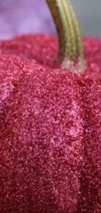 This phone live wallpaper showcases a dazzling red glittered pumpkin resting on a table