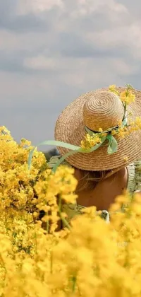 This phone live wallpaper showcases an idyllic scene of a woman in a field of bright yellow flowers wearing a straw hat