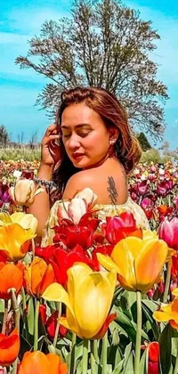Enhance your phone&#39;s display with this stunning live wallpaper featuring a woman amidst a colorful field of tulips, completing a phone call