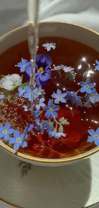 This fascinating live phone wallpaper displays an artistic illustration of a small bowl of tea decorated with lovely blue flowers, adding a serene touch to your device