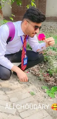 This live phone wallpaper features a man kneeling down holding a flower in a JK uniform