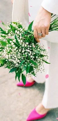 This live wallpaper depicts a stunning bouquet of multi-hued flowers held in the hand of a person with green suit and white dress