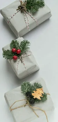 This live phone wallpaper features three wrapped presents with delicate ribbons and bows on top of a table against a concrete art background
