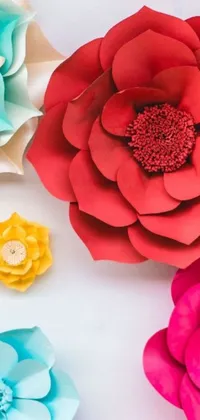 This phone live wallpaper features a stunning arrangement of paper flowers in red, teal, and yellow hues