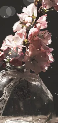 This live phone wallpaper showcases a stunning floral arrangement, featuring a vase filled with pink flowers set against a wooden table