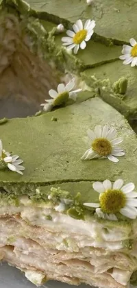 This delectable phone live wallpaper showcases a piece of tempting cake on a pristine white plate, surrounded by daisies and lush green foliage