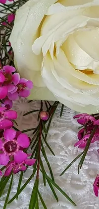 Adorn your phone with a mesmerizing live wallpaper featuring a white rose and pink flowers on a table