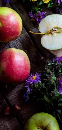 This phone wallpaper depicts a stunning still life of apples resting on a wooden table