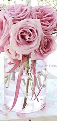 Enjoy the beauty of nature with this stunning live wallpaper featuring a vase filled with pink roses sitting on a table