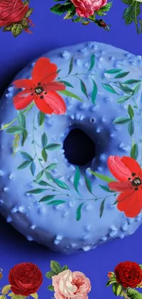 This phone live wallpaper features a beautifully decorated donut adorned with flowers lying on a blue surface