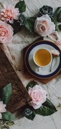 This live wallpaper for phones is a beautiful still life of a book placed on a bed with rose petals and a cup of tea beside it