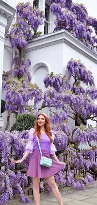Decorate your phone background with a vibrant live wallpaper of a stunning woman standing in front of a beautiful flowering tree