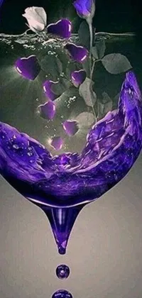 Get mesmerized by this stunning live phone wallpaper featuring an exquisite glass filled with purple liquid placed on a clear table