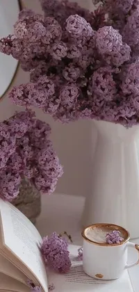 This live wallpaper showcases a white vase filled with purple lilac flowers beside an open book on a white background