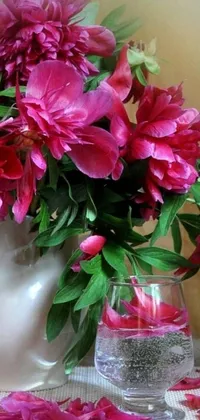 This charming live wallpaper depicts a vase brimming with pink flowers on a stylish table, accompanied by an artistic portrait and drink