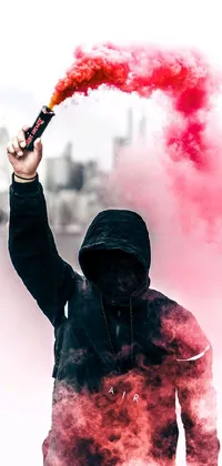 This phone live wallpaper features striking digital art of a man in a black and red cape and hoodie holding a red banner and hand grenades, with red smoke coming out of his mouth