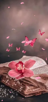 This live wallpaper features a pink flower on an open book, along with a butterfly goddess of fire, emoji symbols, and orchid petals