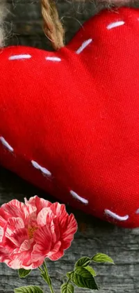 This lovely phone wallpaper showcases a red heart and carnation perched on a wooden table