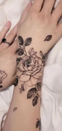 This tattoo-inspired phone live wallpaper features a close-up view of black flower tattoos on someone's hands