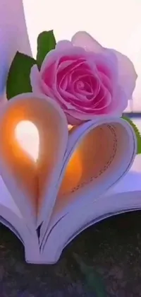 This live wallpaper features a pink rose on top of an open book, accompanied by a glowing heart