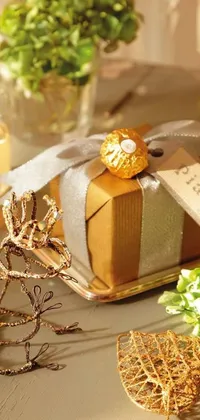 This phone live wallpaper features a small gift box on a table with a grey and gold color scheme