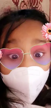 This live phone wallpaper features a young girl wearing sunglasses and a face mask while a beautiful scrolling picture appears in the background
