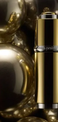 This stylish live wallpaper features a bottle of perfume displayed on shiny golden balls, against a liquid metal background