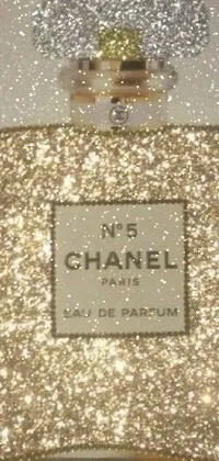 This phone live wallpaper features a glittering bottle of Chanel perfume resting on a silver and gold-trimmed table