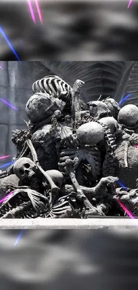 This phone live wallpaper features a group of spooky skeletons seated on a pile of skulls