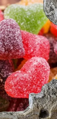 This lively phone live wallpaper features a colorful bowl of gummy bears arranged against a rocky backdrop
