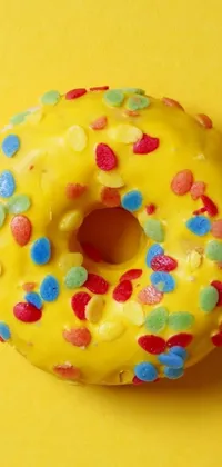 This phone live wallpaper showcases a tantalizing image of a doughnut with sprinkles on a bright yellow surface, designed to brighten up your mobile device
