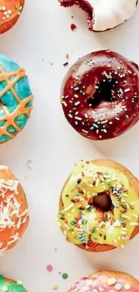 This phone live wallpaper features a playful scene of colorful doughnuts with sprinkles arranged on a table