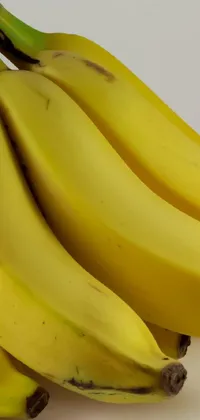 This live phone wallpaper features a high-detailed photo of multiple bananas on top of a table