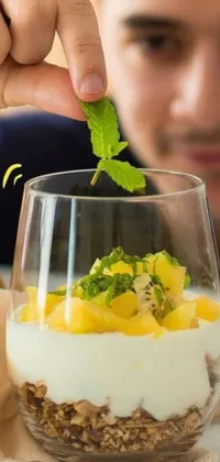 Looking for a mouth-watering phone wallpaper? Look no further than this close-up shot of a delectable dessert being added to a glass! The glass is filled with a sea of smooth parfait, with juicy chunks of fresh mango throughout