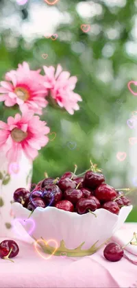 This phone live wallpaper features a beautiful bowl of cherries and pink flowers on a table, perfect for nature lovers