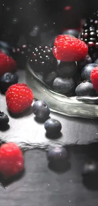 This live wallpaper depicts a glass bowl filled with vibrant raspberries and blueberries