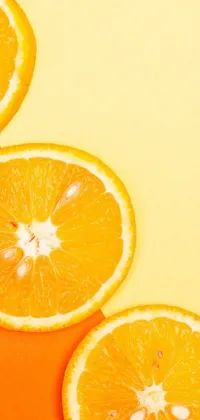 This phone live wallpaper features a realistic image of orange slices arranged on a table with a yellow background