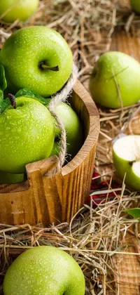 Looking for a beautiful phone wallpaper that perfectly captures the autumn harvest season? Look no further than this stunning live wallpaper featuring a wooden bowl filled with green apples
