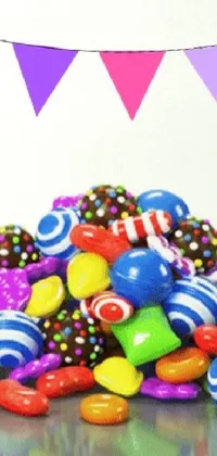 This live phone wallpaper features a vibrant pile of candy on a table, surrounded by colorful party balloons and scattered chocolate and lollipops