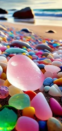 Looking for a striking live wallpaper for your phone? Check out this picturesque image featuring a heap of sea glass placed on a sandy beach