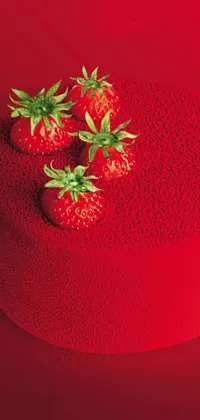 This phone live wallpaper depicts a vibrant image of two strawberries sitting on a red cake