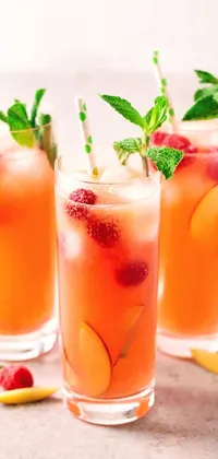 This phone live wallpaper features three glasses filled with drinks and decorated with raspberries, tumblr, peaches, seraphine, and mint leaves