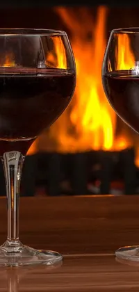 This live phone wallpaper depicts a romantic scene with two wine glasses, a bottle of wine, and a warm fireplace